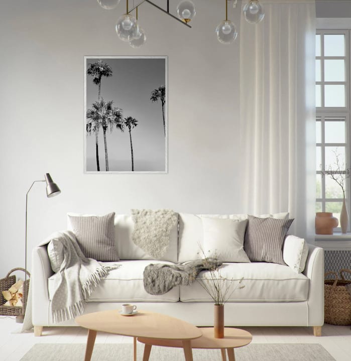 Woman adjusting California coastal wall art in sunny living room
