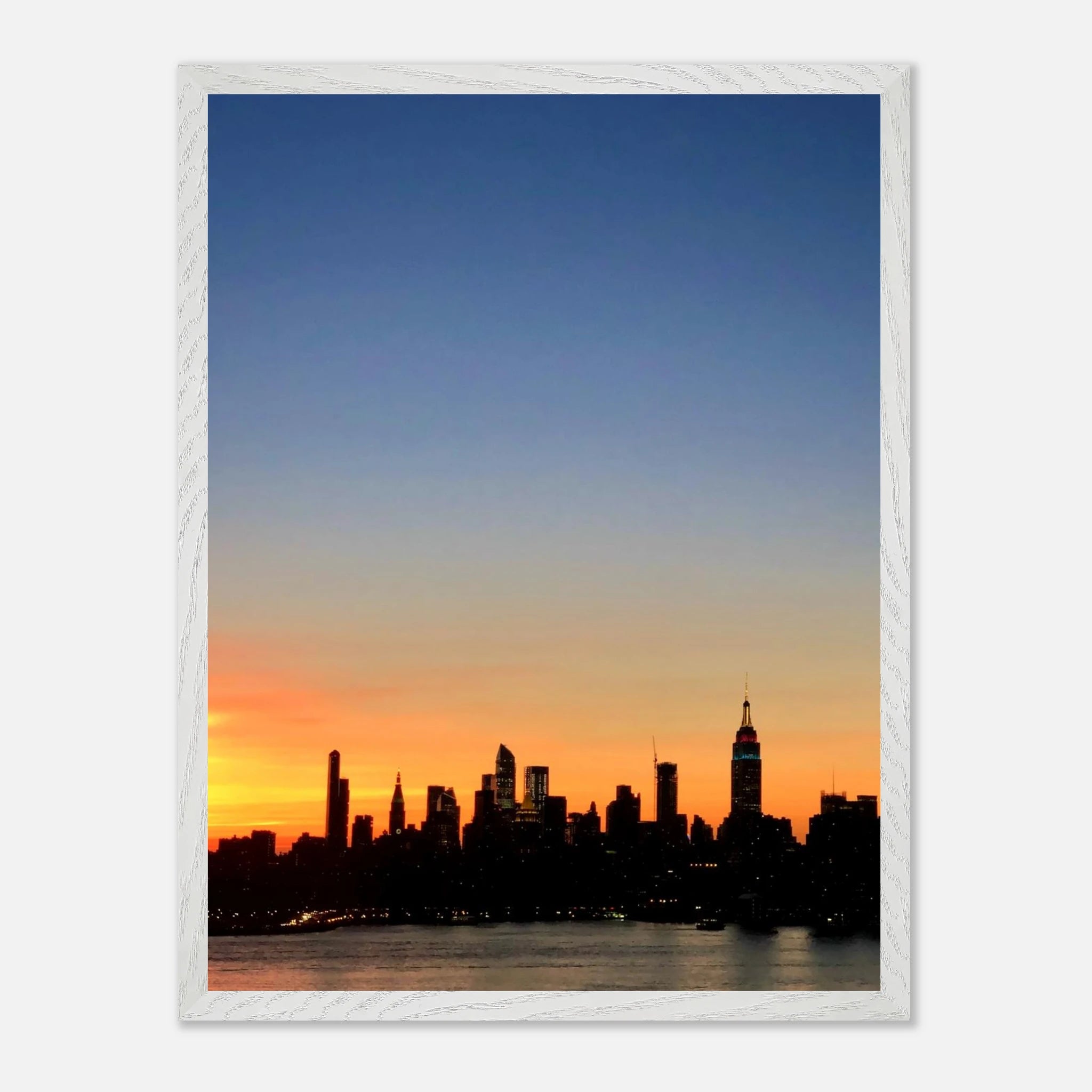 Wooden framed poster of the Manhattan skyline at sunset, featuring vibrant cityscape art for stylish home décor.