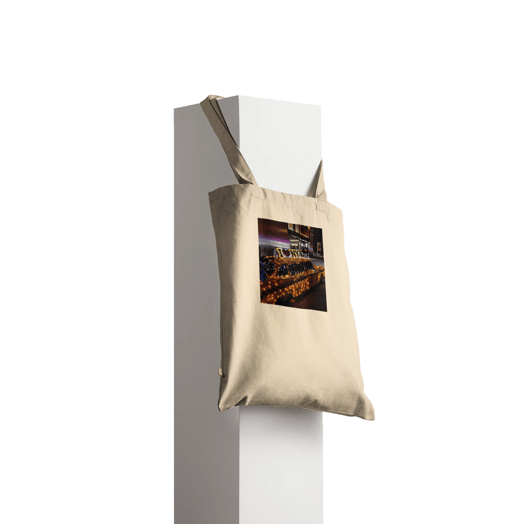 Eco-friendly cotton tote bag with NYC taxi cab holiday magic print, featuring a natural design and spacious carrying capacity.